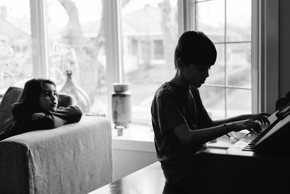 boy at piano girl listens - Documentary Family Photography