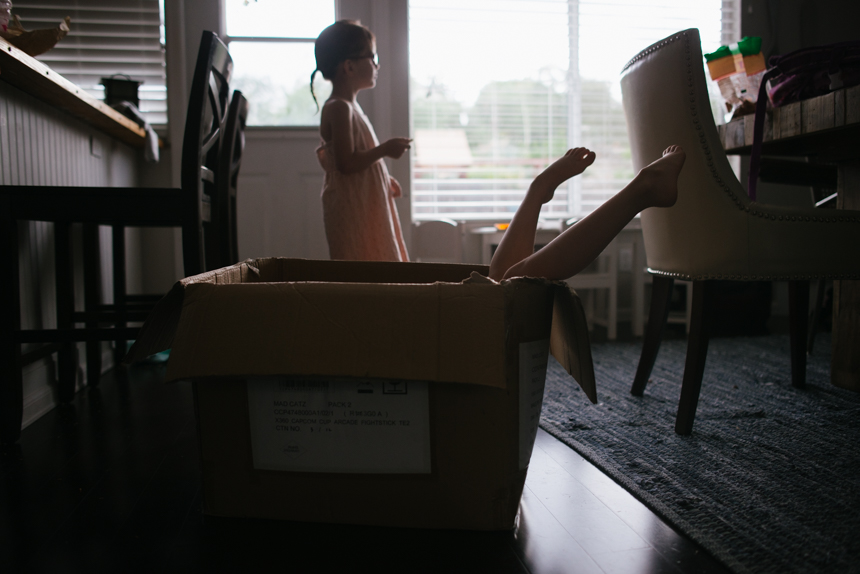 child's feet stick out of storage bin - Documentary Family Photography