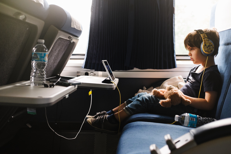 boy with headphones on train - Documentary Family Photography