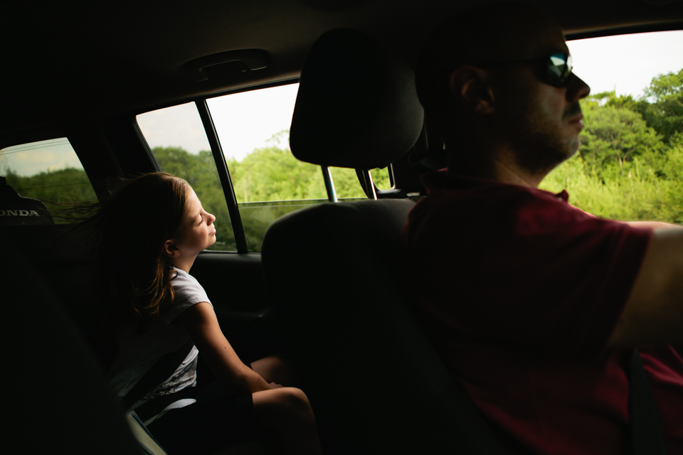 girl looks out car window - Documentary Family Photography