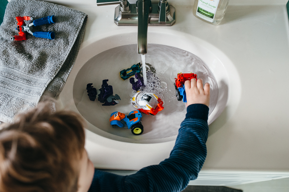 boy plays with toys in sink - Documentary Family Photography