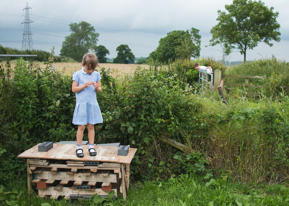 girl standing on palettes in field - Documentary Family Photography