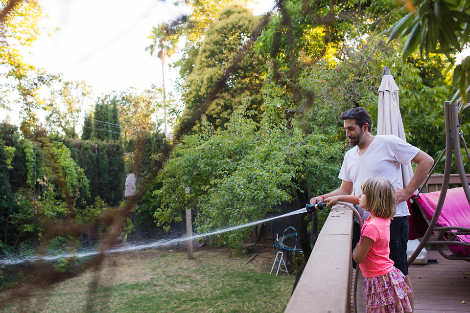 Father and daughter with garden hose - Documentary Family Photography