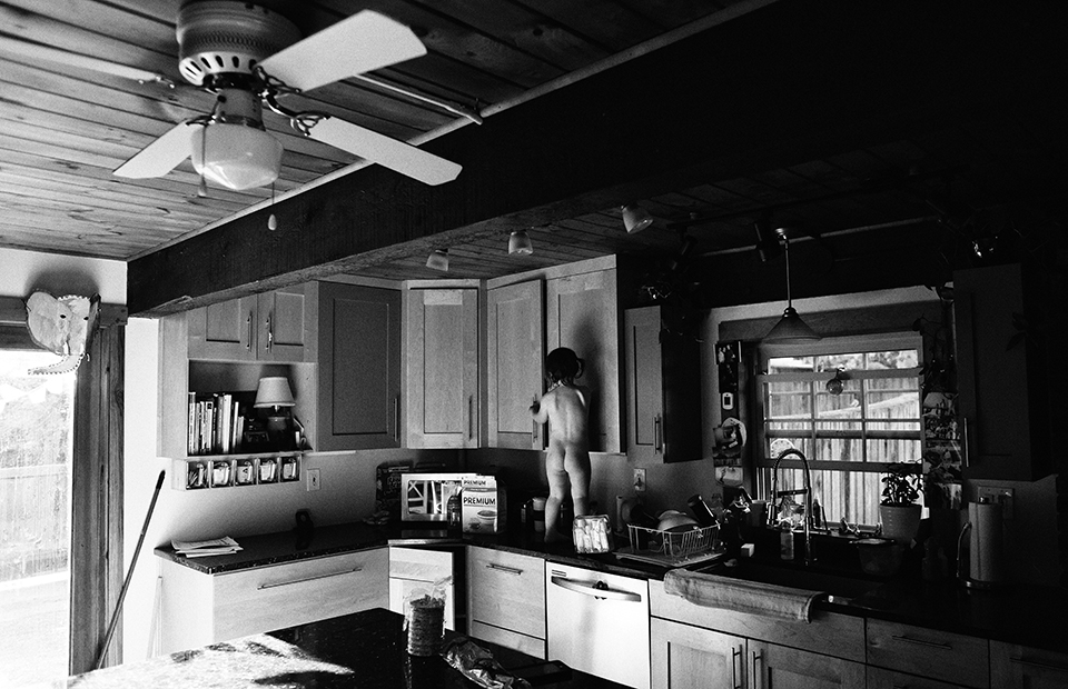 child on counter digs through cabinets