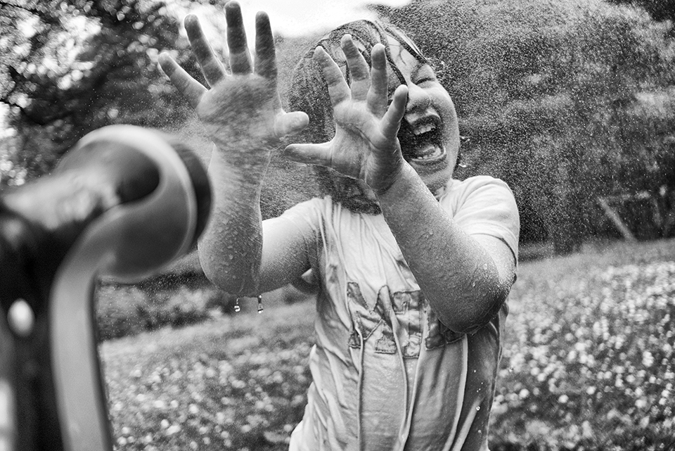 child getting sprayed with hose
