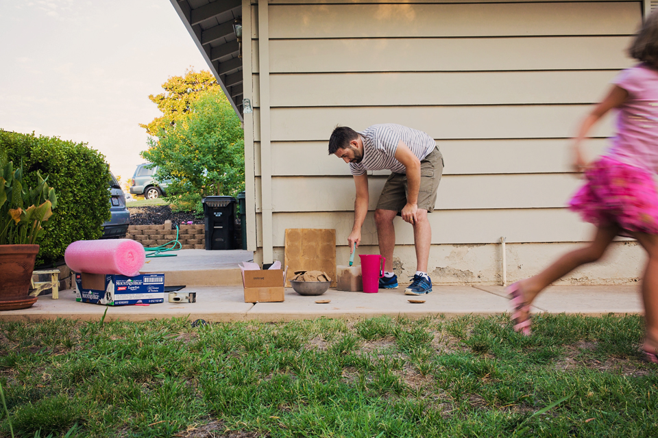 father cleaning yard while child runs - Documentary Family Photography