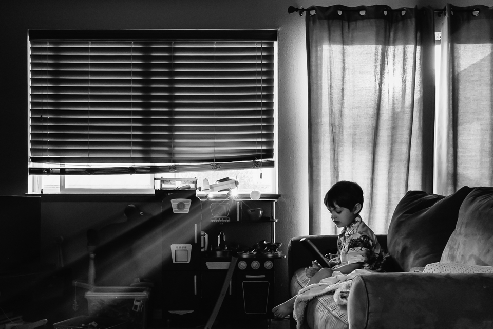 child on couch with light streaming in - Documentary Family Photography