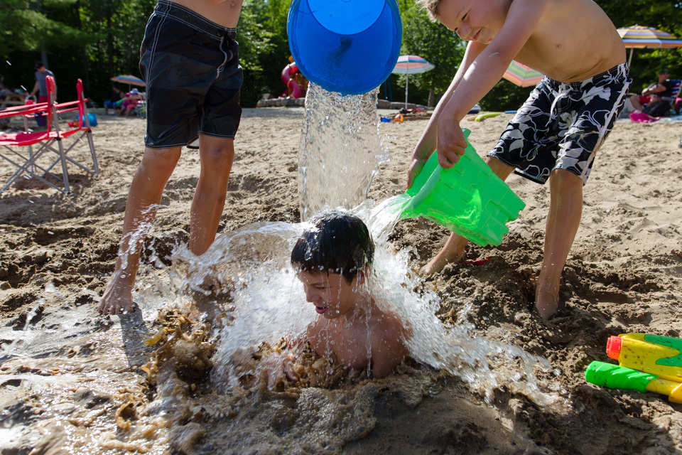 buried boy gets doused with water buckets - Documentary Family Photography