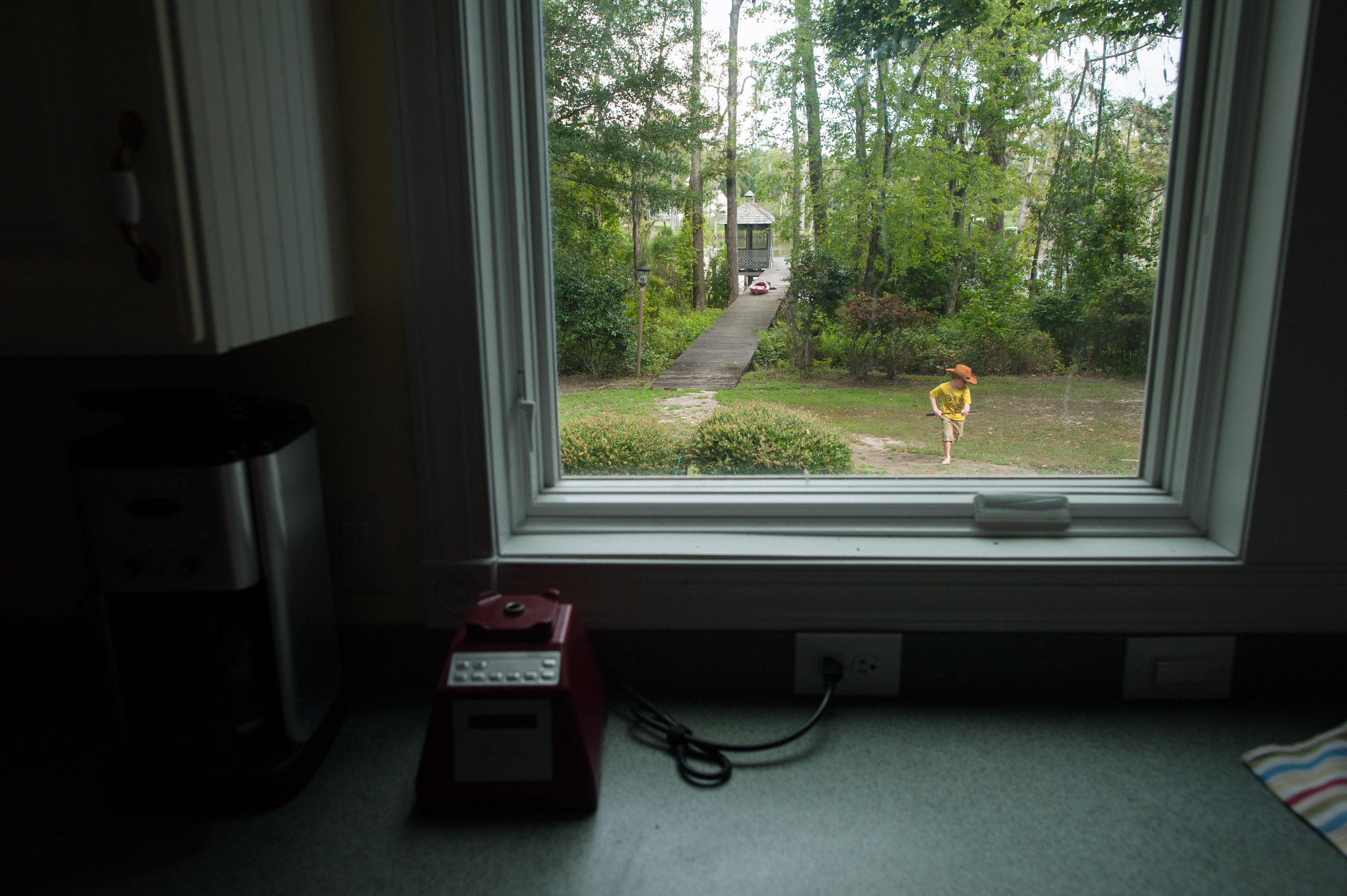 child playing cowboy through window - Documentary Family Photography