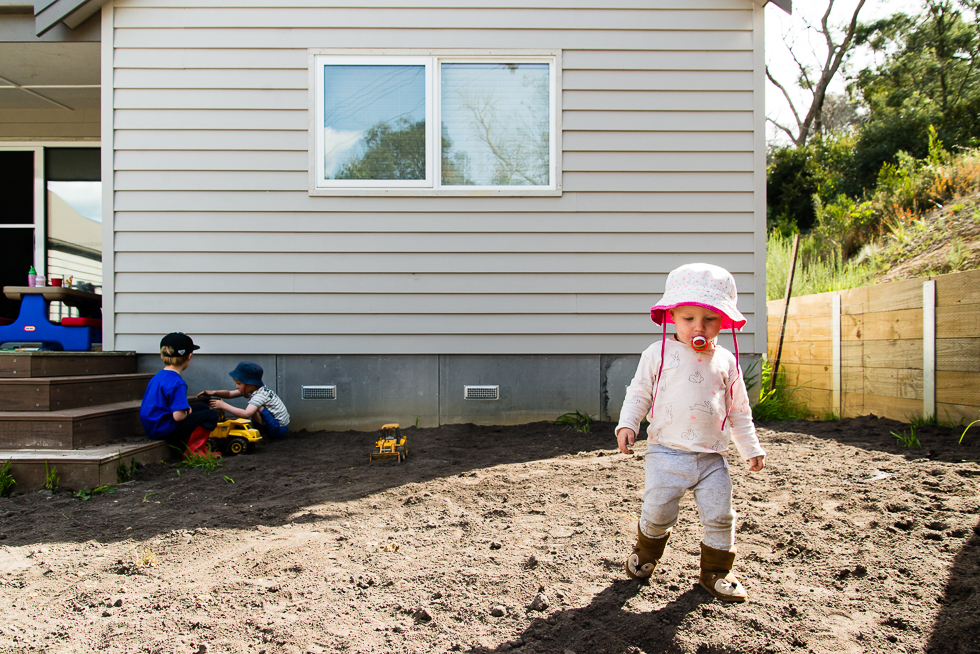 girl in hat walks through mud - Documentary Family Photography