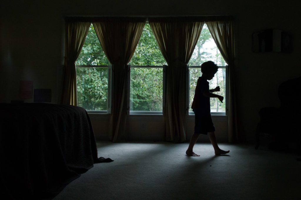 silhouette of boy walking across room - Documentary Family Photography