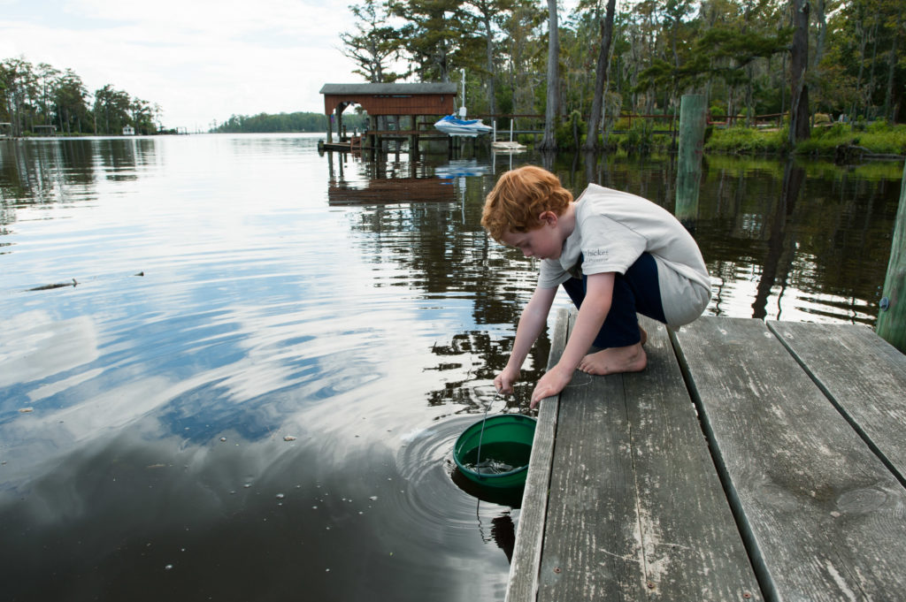 boy pulls up bucket from dock - Documentary Family Photography