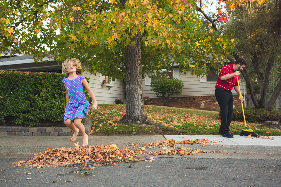 girl jumps in leaf pile - Documentary Family Photography