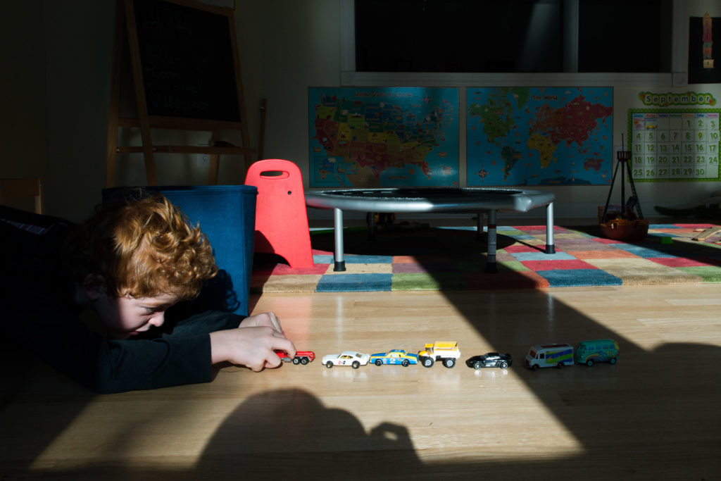 boy lines up toy cars - Documentary Family Photography