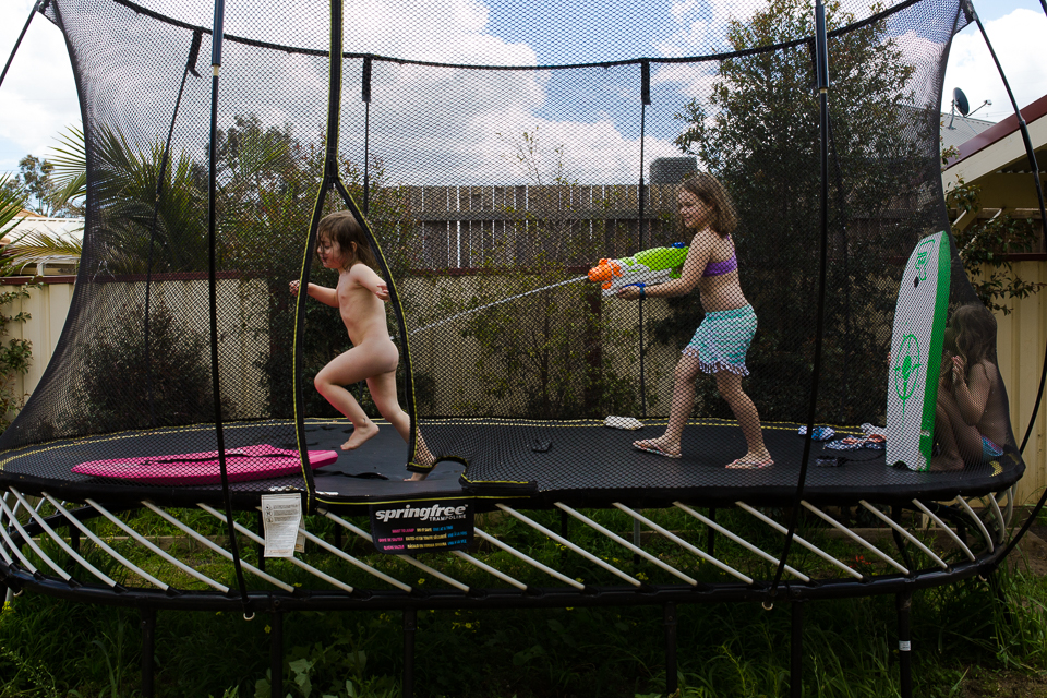 Kids with water gun on trampoline - Documentary Family Photography