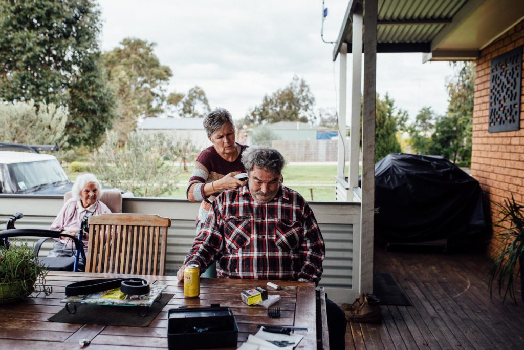 older woman gives older man haircut outside - Documentary Family Photography