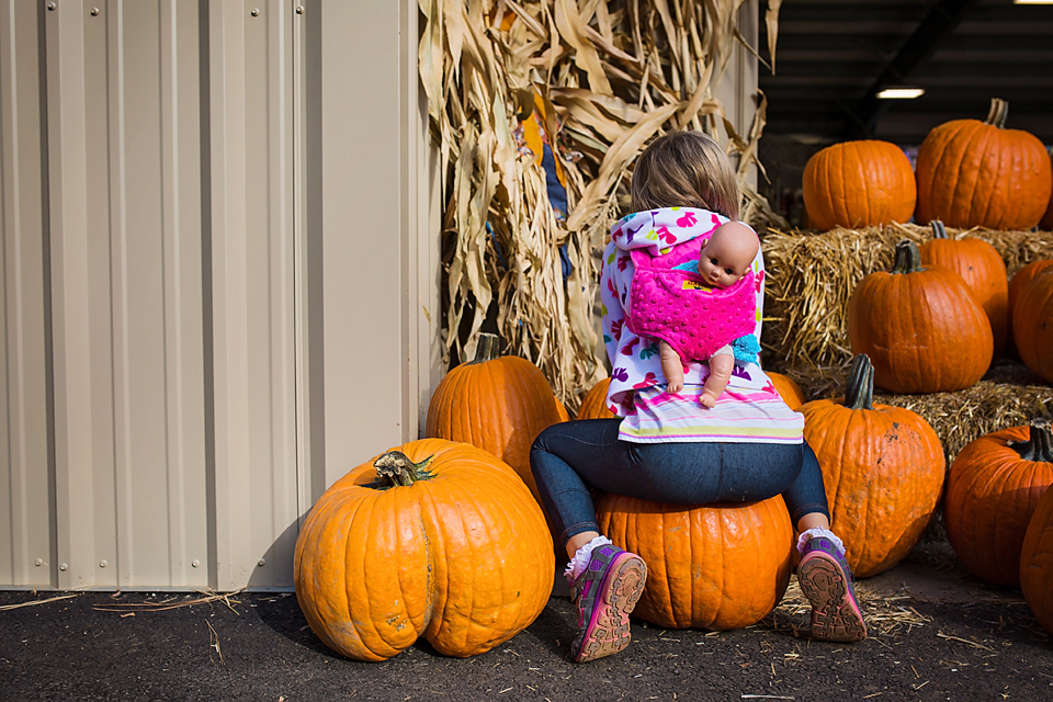 girl sits on pumpkin - Documentary Family Photography