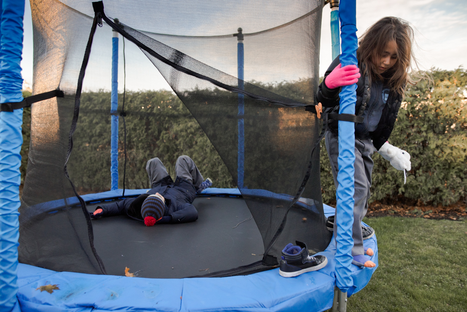 kids in jackets on trampoline - Documentary Family Photography