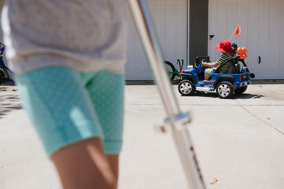 kids on riding toys in drive - Documentary Family Photography