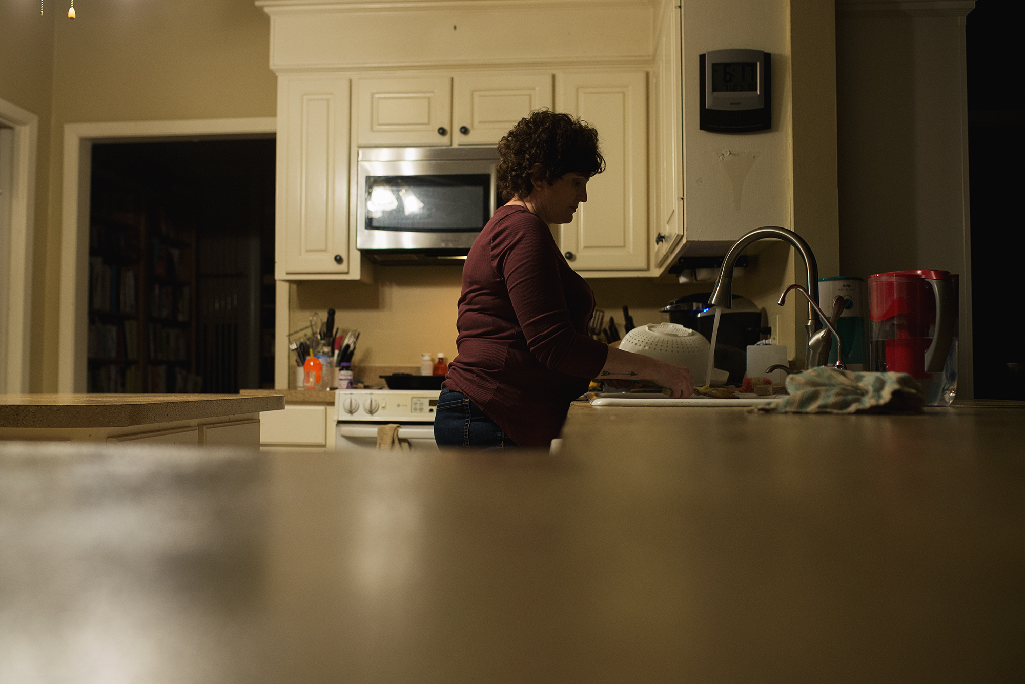 woman washes dishes at sink