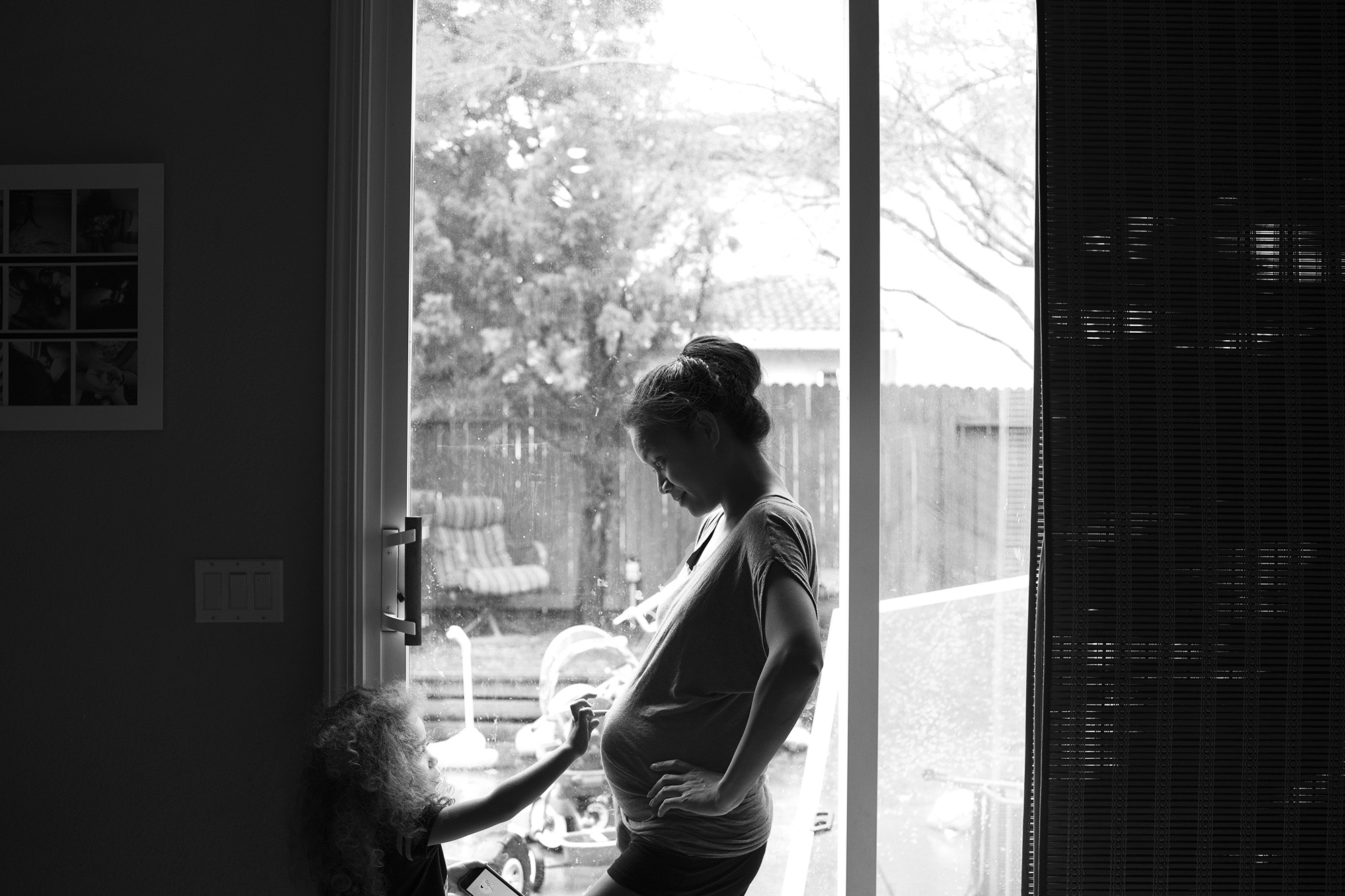 pregnant woman at window with daughter - documentary family photography