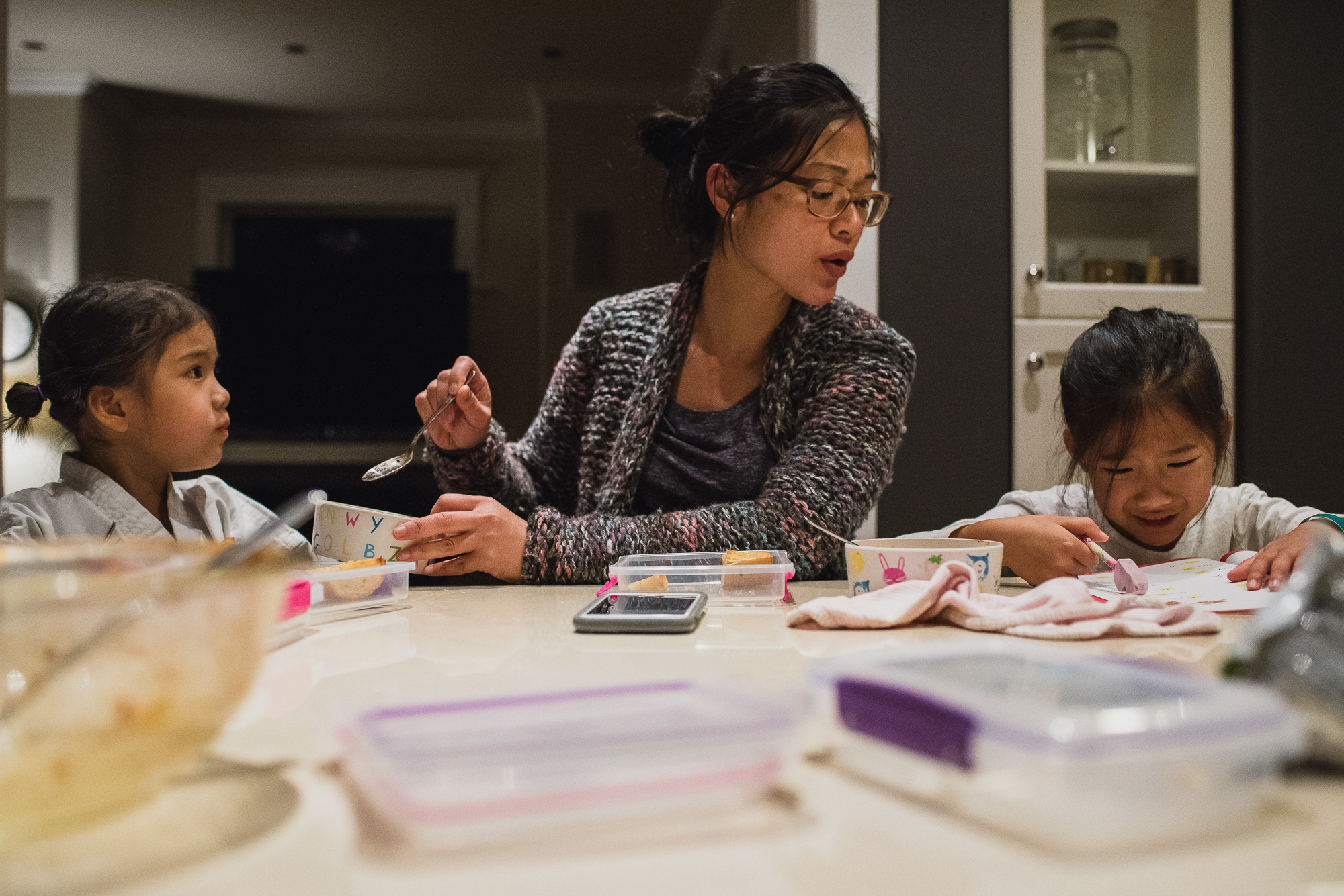 mother with children doing homework and eating dinner - documentary family photography