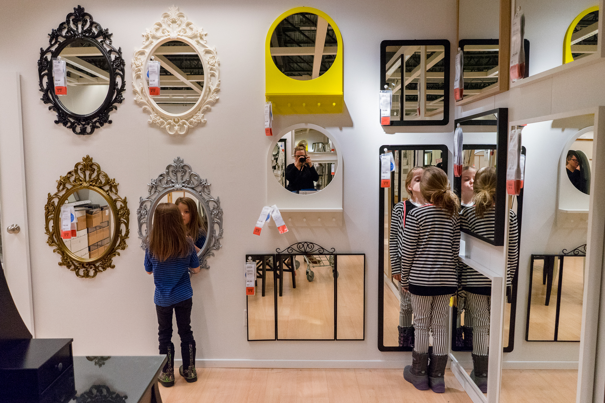 girls make faces in mirror at store -documentary family photography