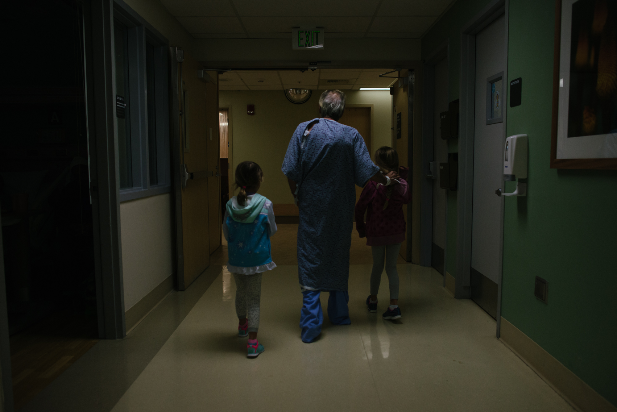 man walks with children in hospital hallway - documentary family photography