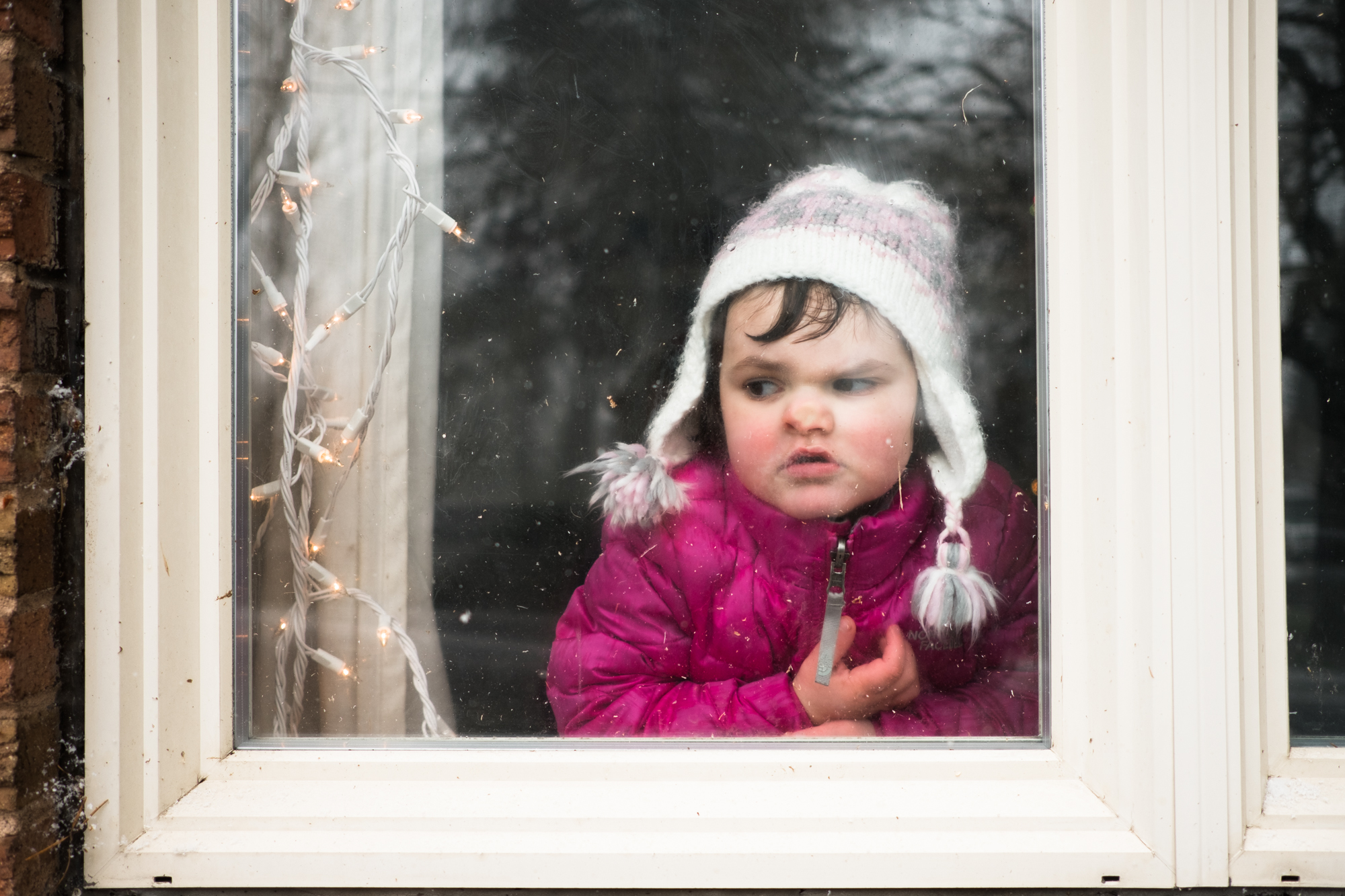 girl shoves face against window - documentary family photography