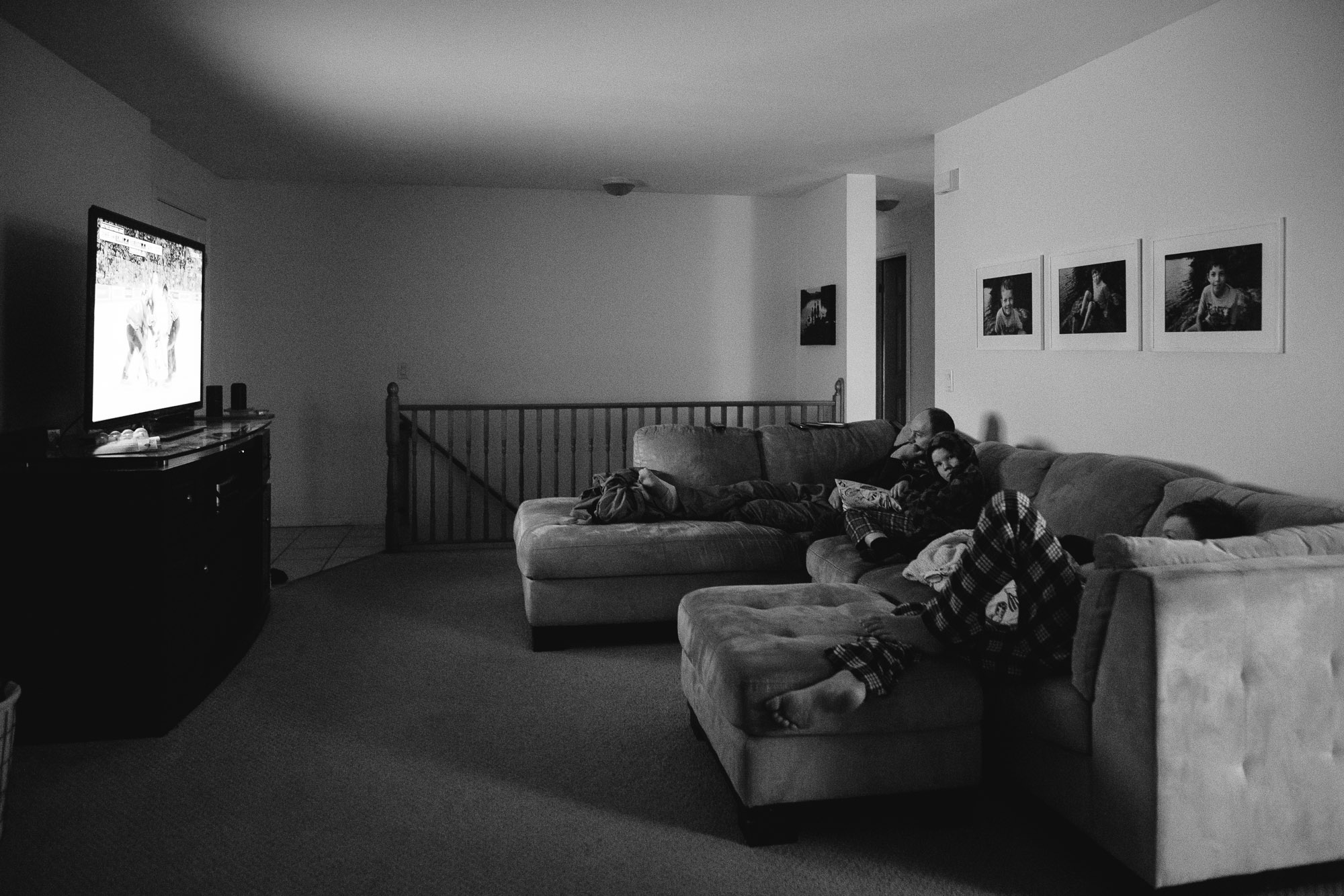 family watches TV on couch - documentary family photography