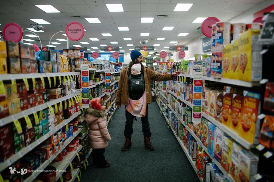 father carries baby in drug store - documentary family photography