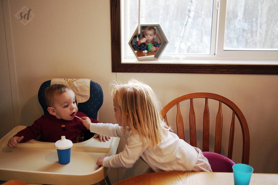 girl feeds baby - documentary family photography