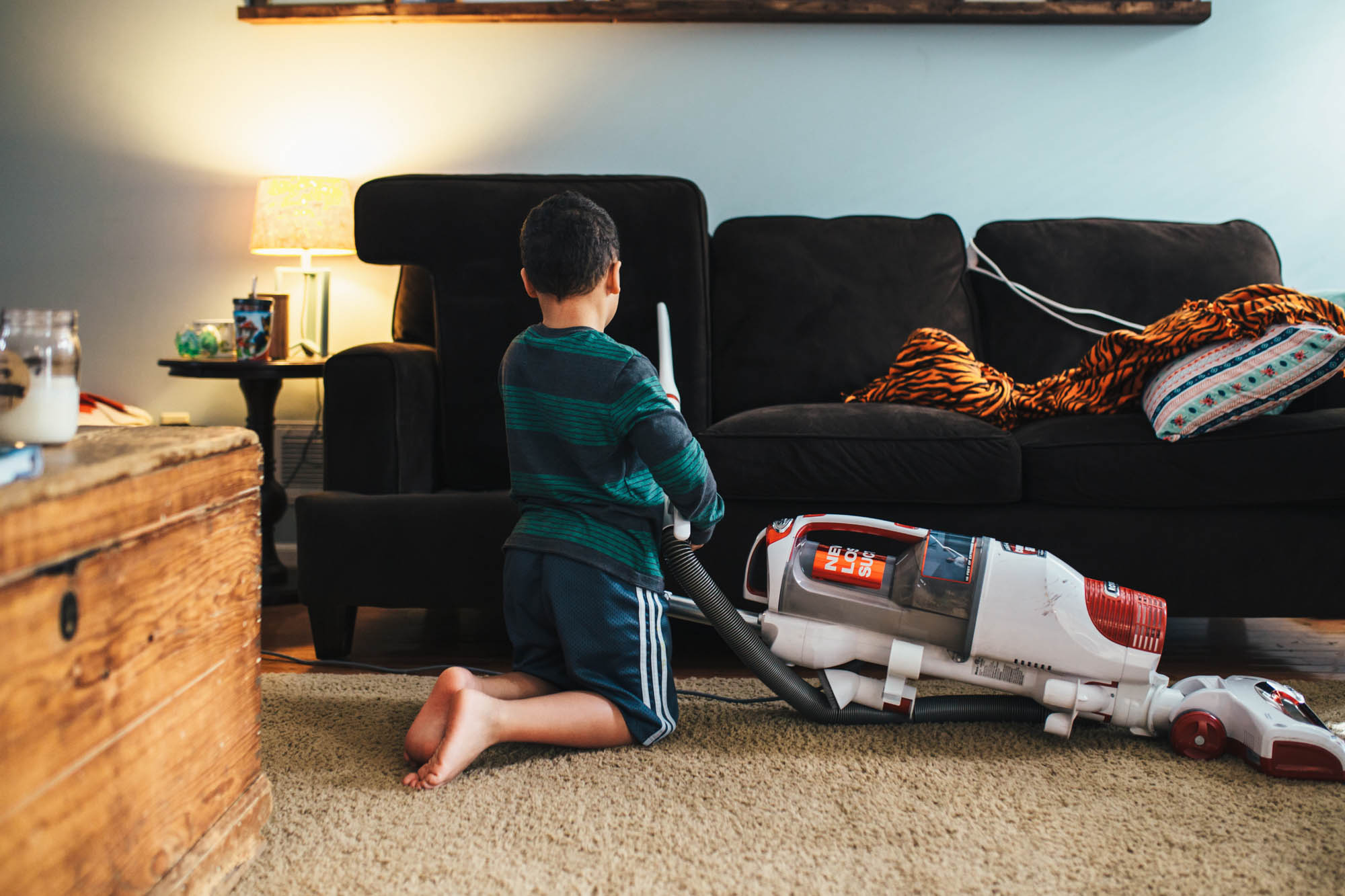 Boy vacuums couch - documentary family photography
