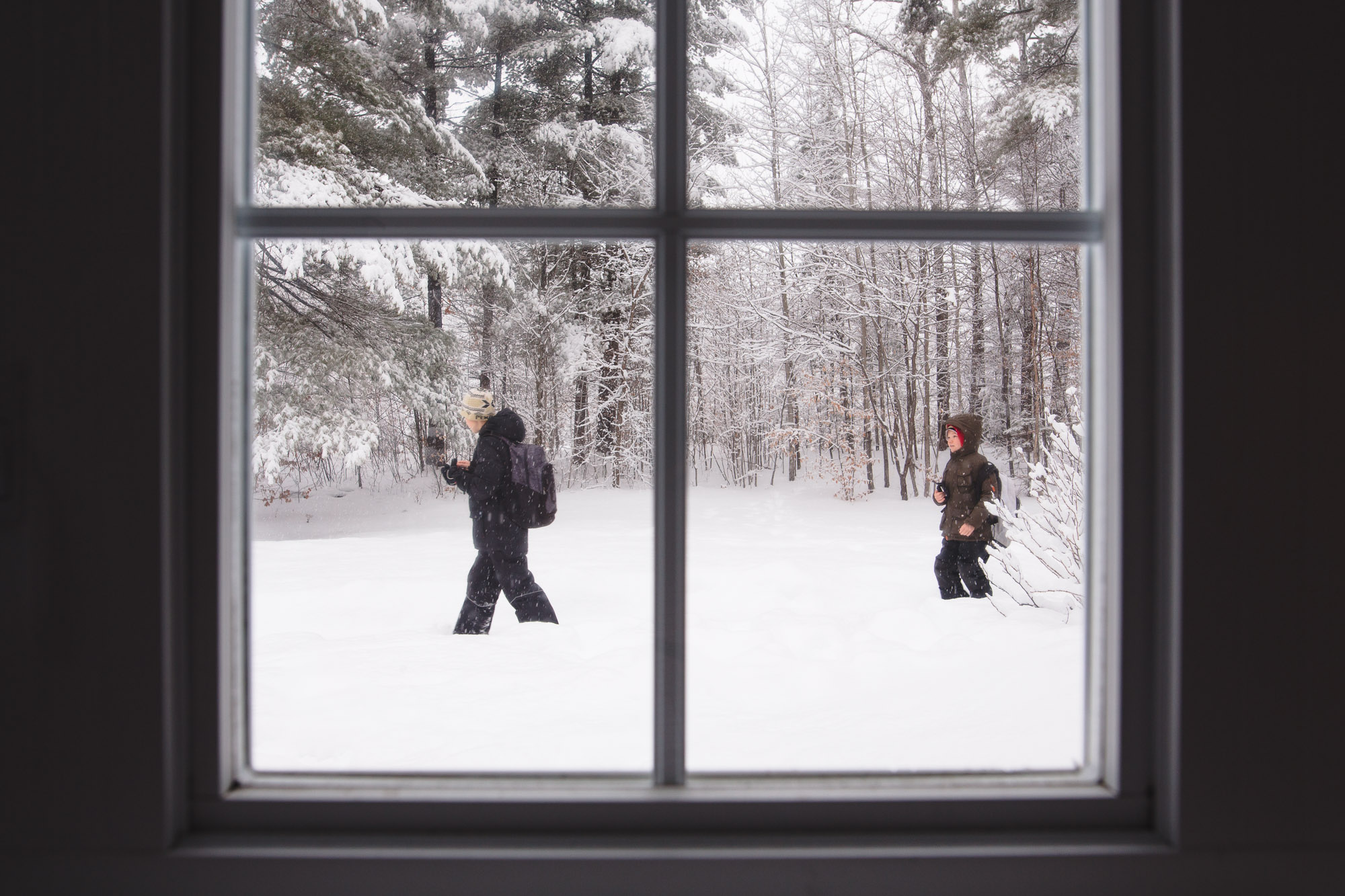 kids walking through snow from window - documentary family photography
