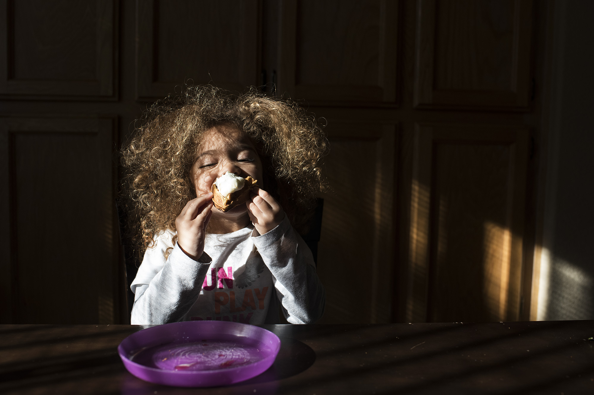 girl eat cupcake in spot of sunlight - documentary family photography