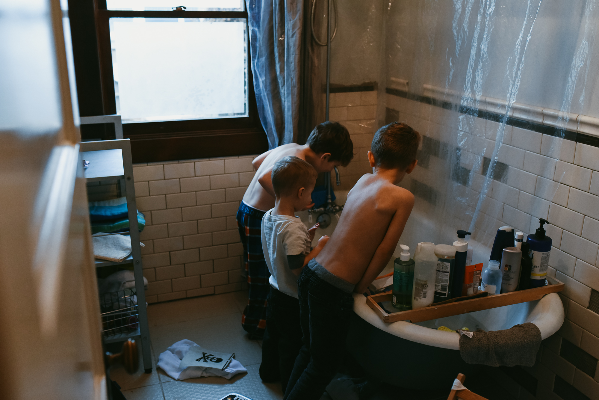Kids huddle around bathtub - documentary family photography