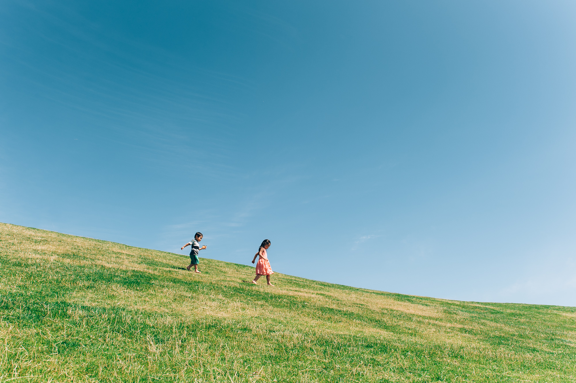 girl and boy walking down grassy hill