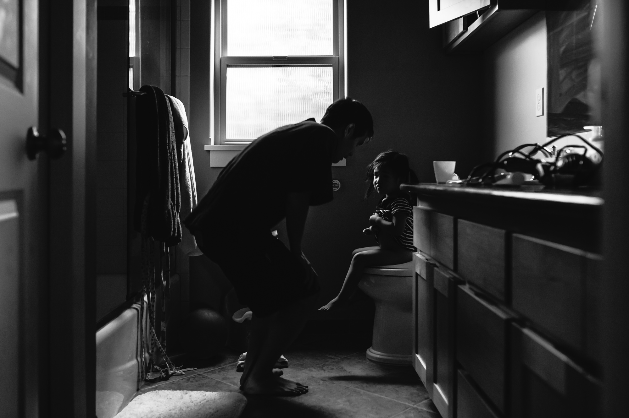 father helping little girl on potty