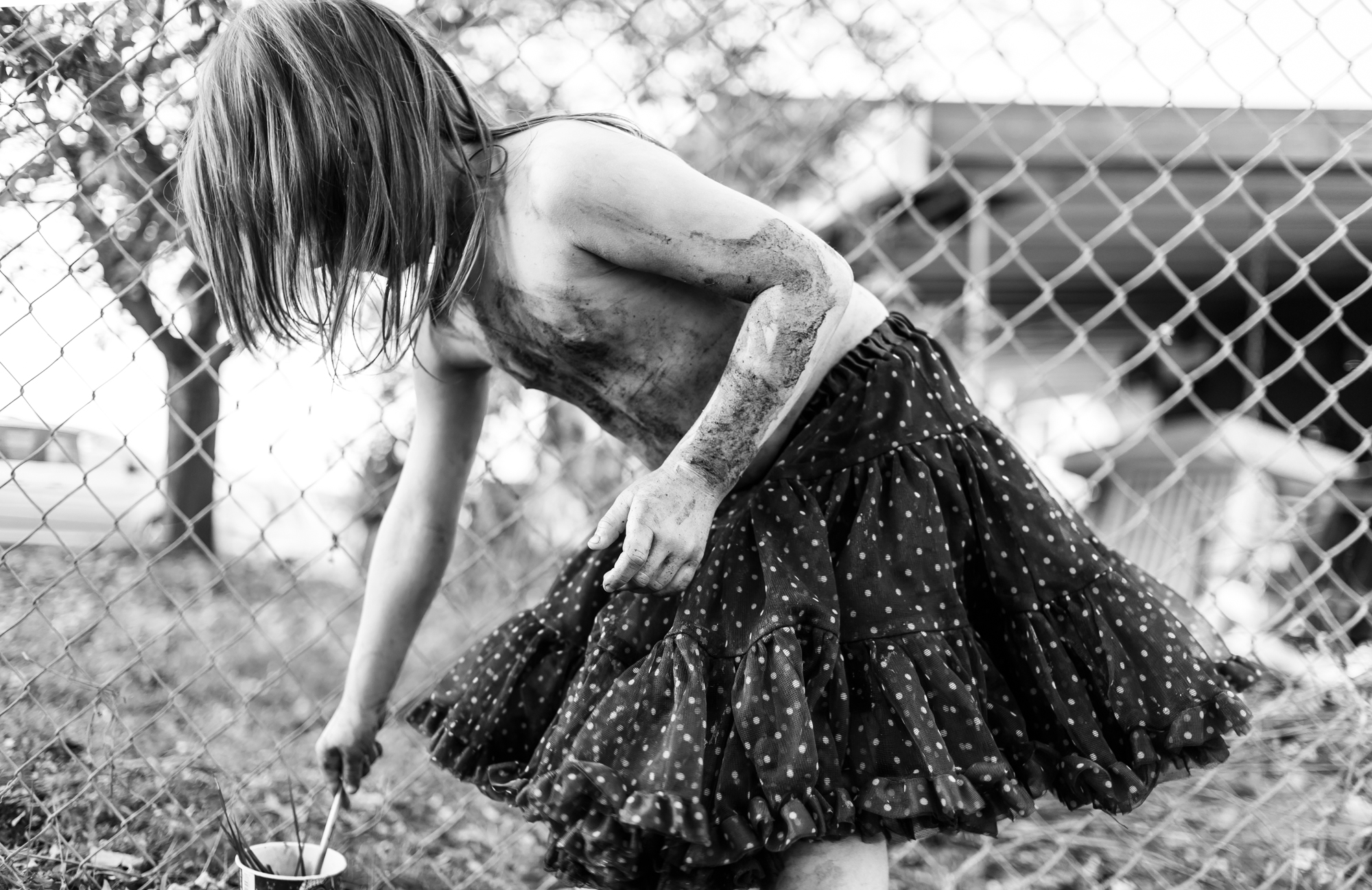 girl covered in dirt with paint brushes