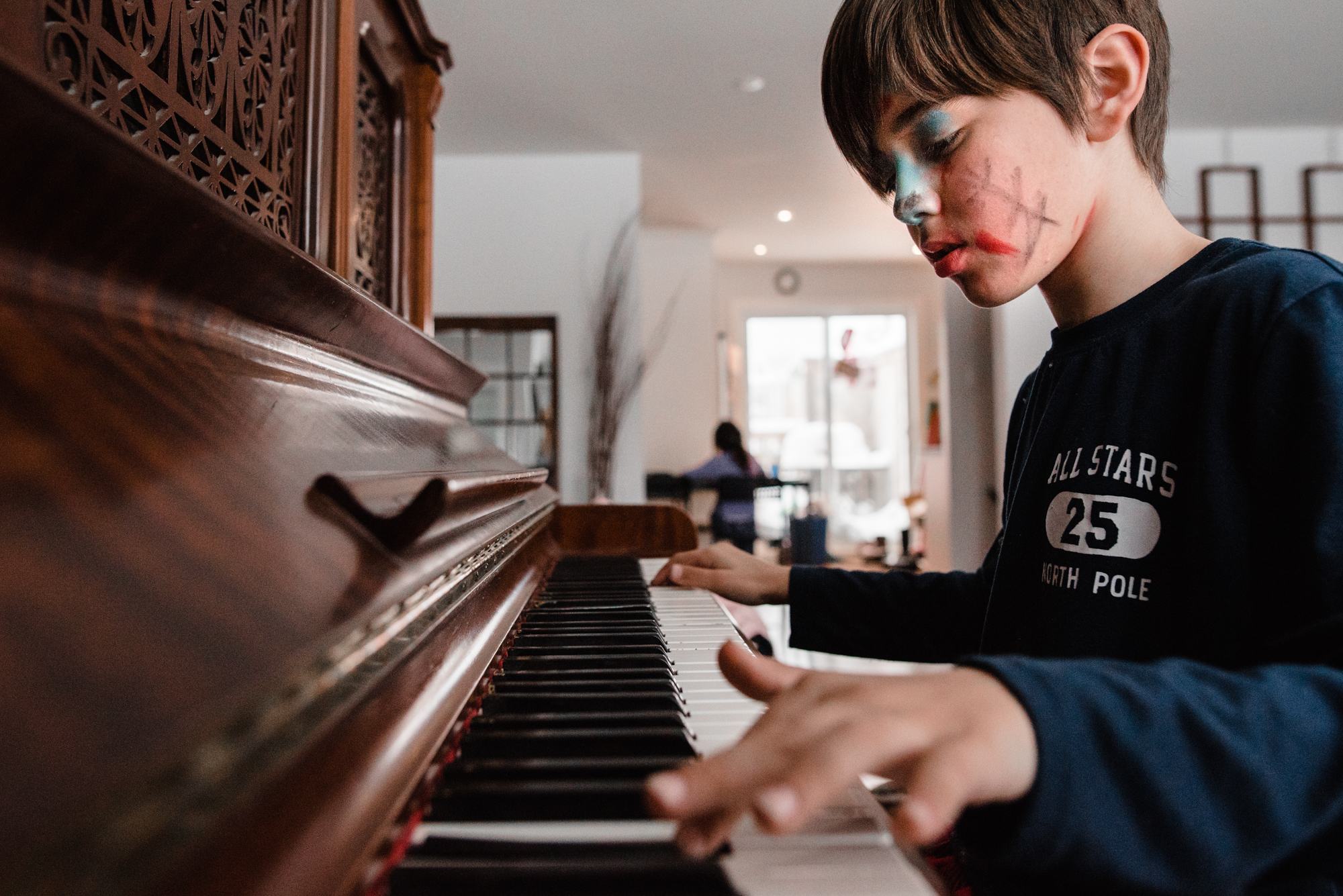 boy with face paint plays piano - Documentary Family Photography
