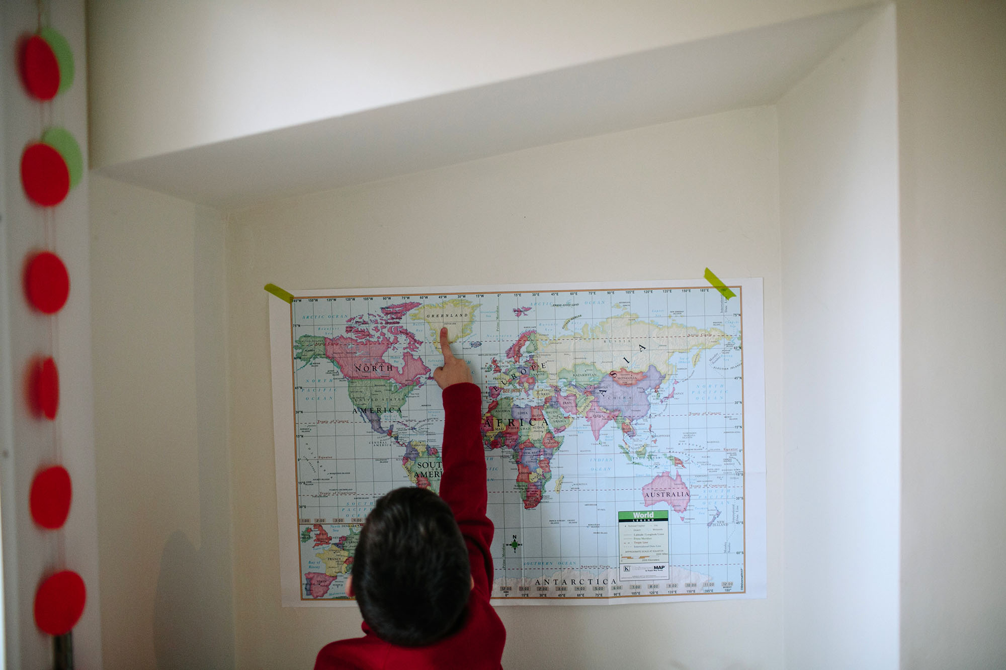 child points at spot on map - documentary family photography