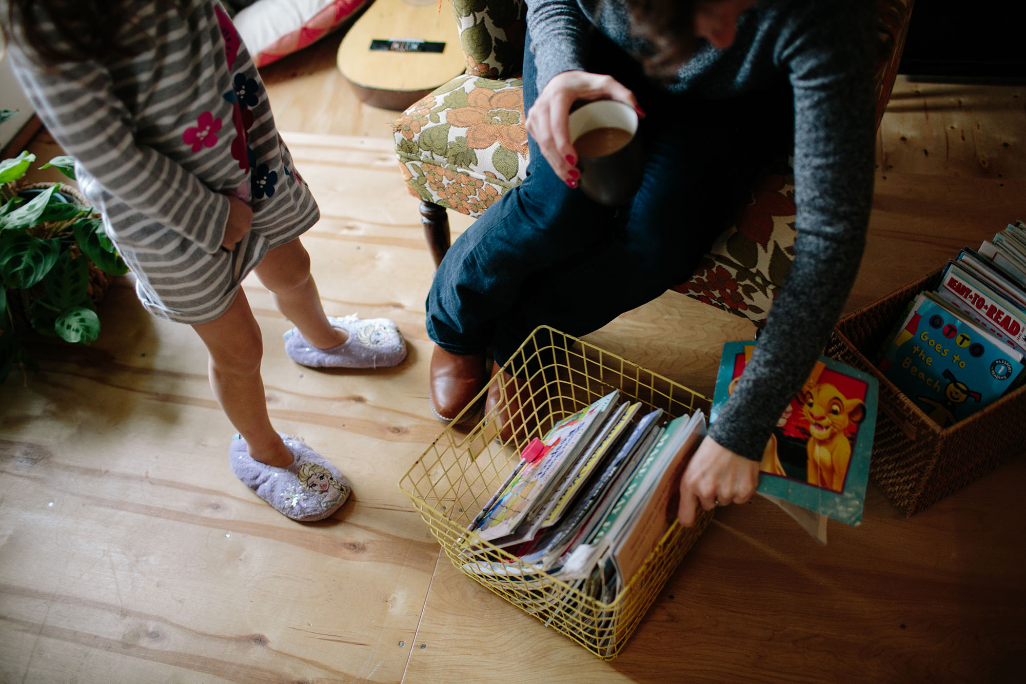 mother reaches for books while holding coffee - documentary family photography
