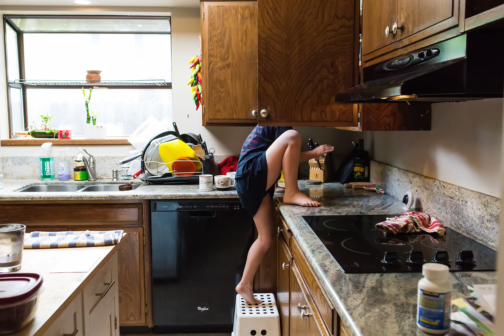 girl looking in kitchen cabinet - Documentary Family Photography