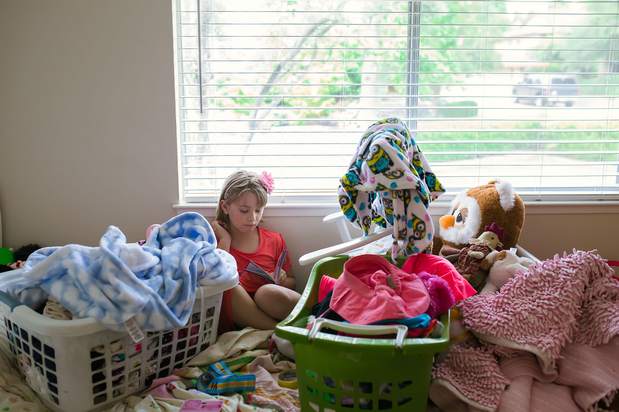 girl sits amongst household clutter - documentary family photography