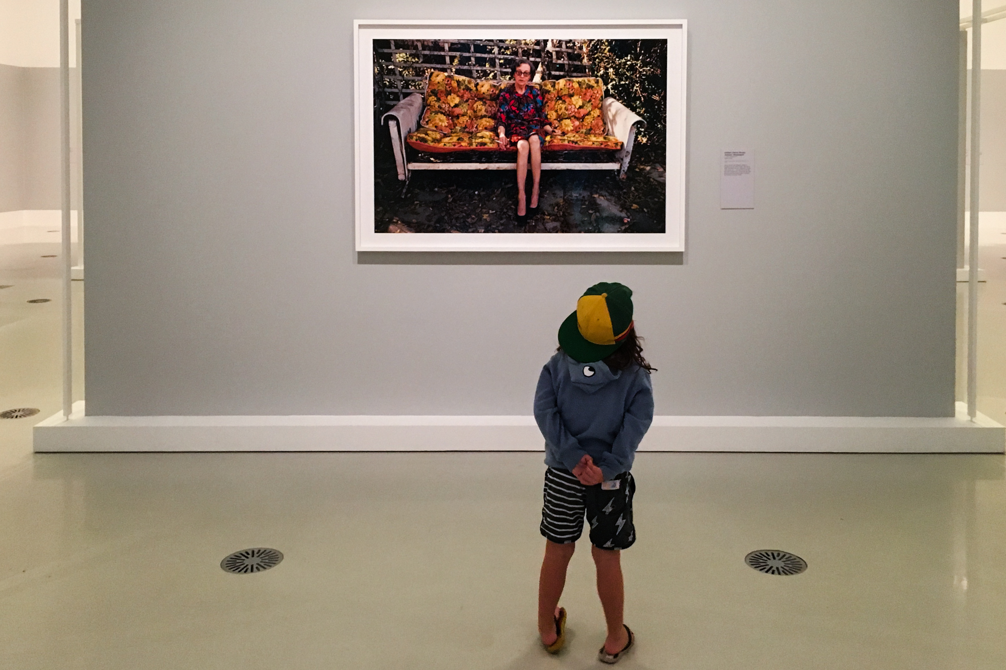 child looks at photograph in gallery - Documentary Family Photography