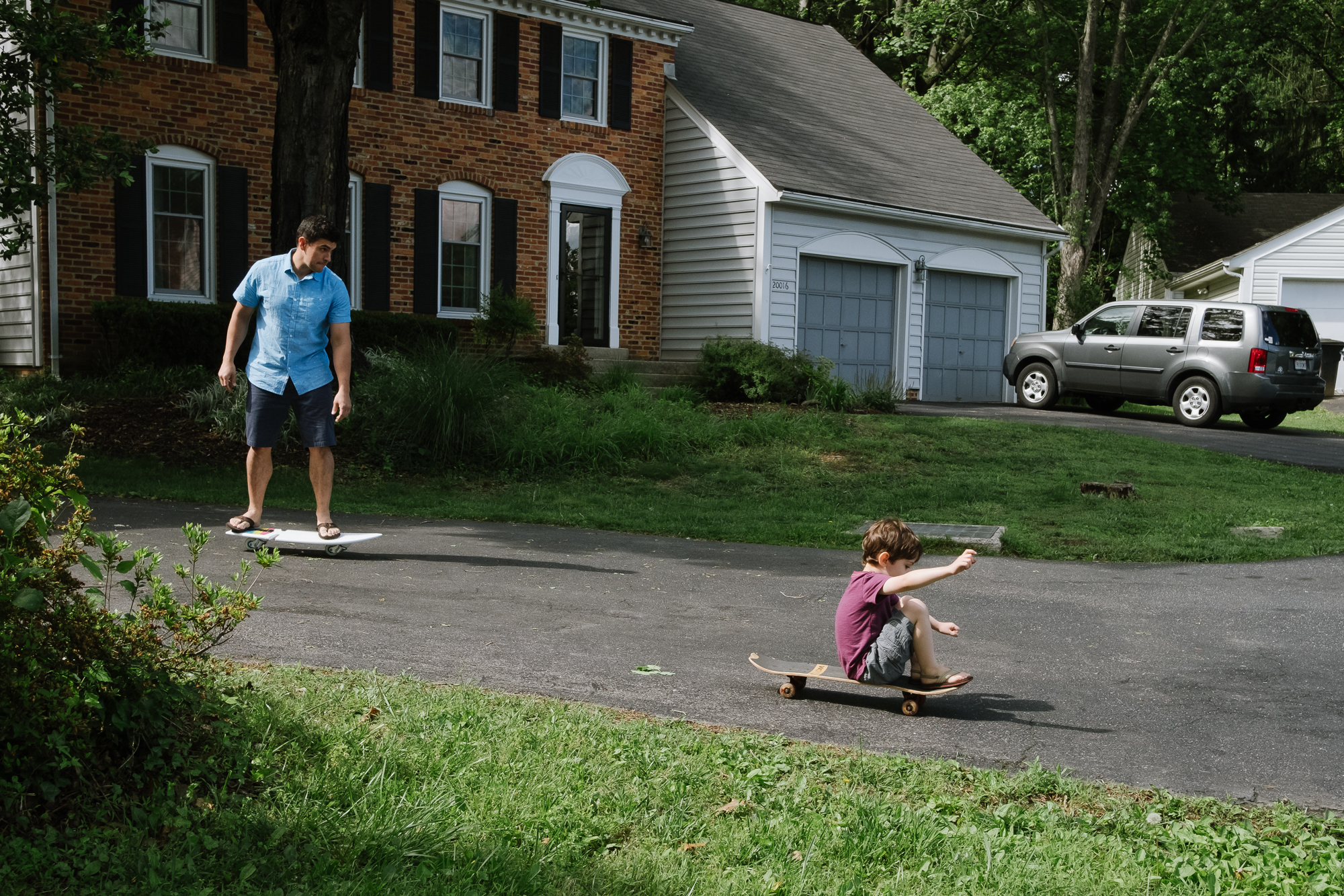 father and son skateboard in driveway - documentary family photography