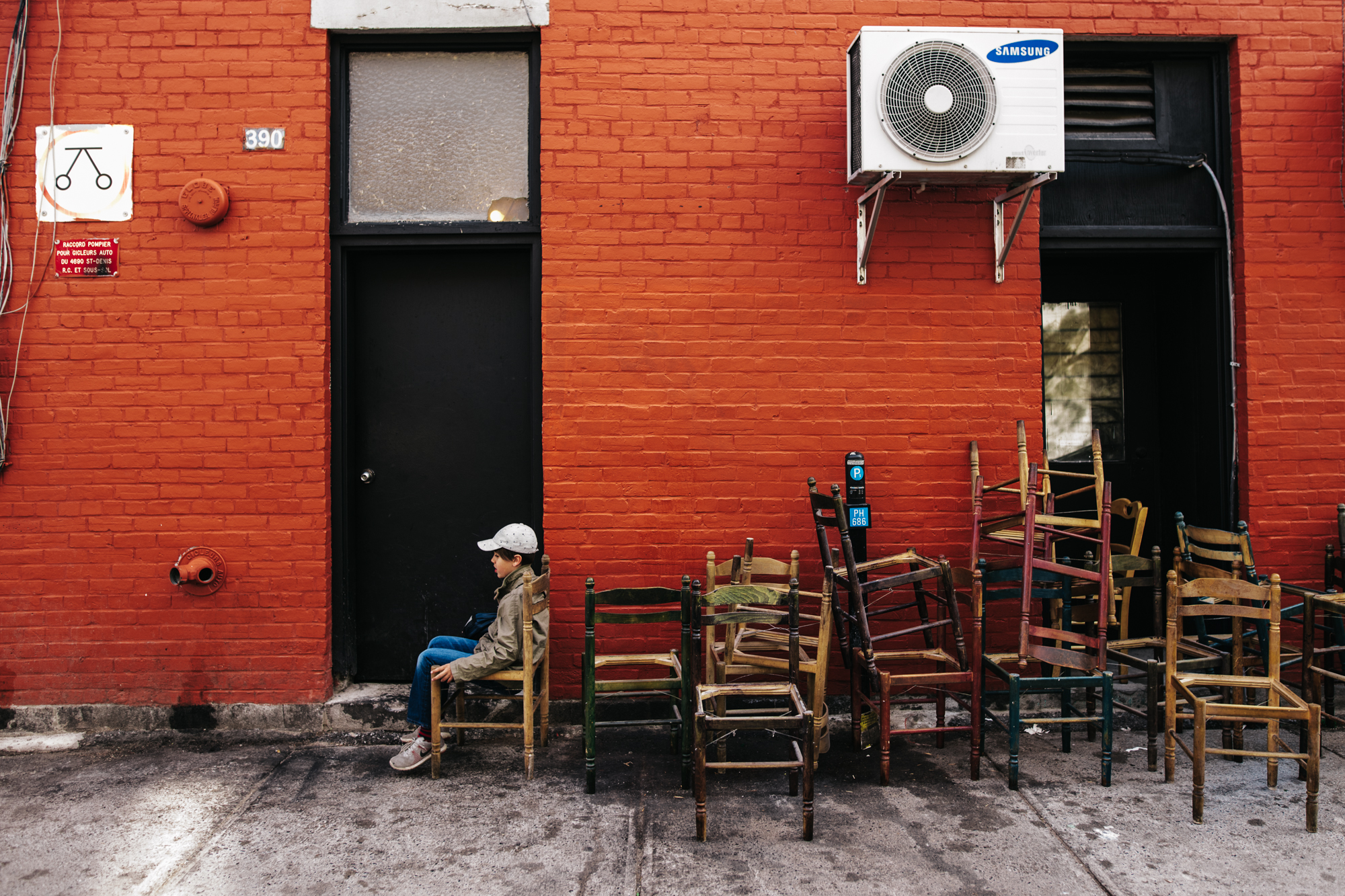 boy sitting in old chairs in alley - documentary family photography