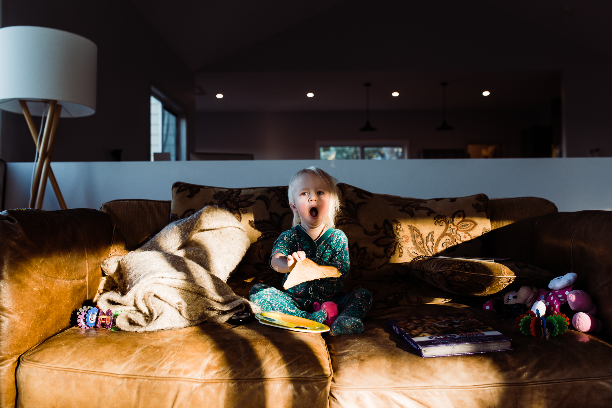 girl yawns on sun dappled couch - documentary family photography