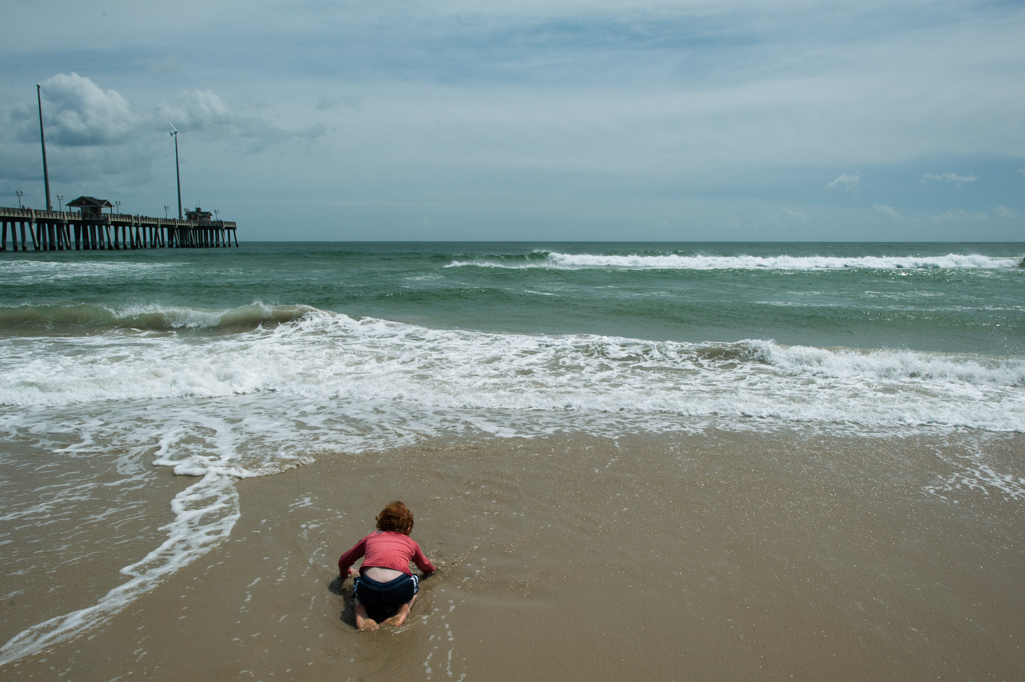 boy wades in waves on beach - documentary family photography