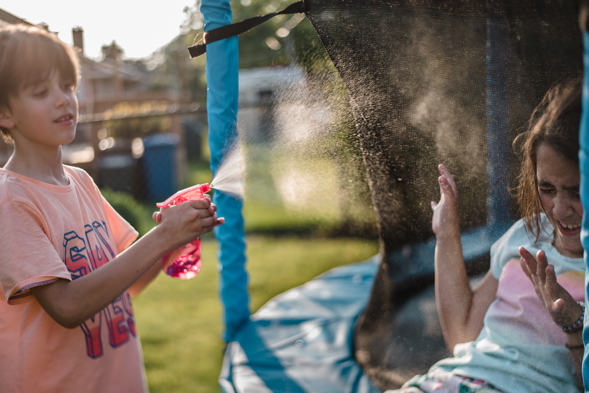 kids with spray bottle on trampoline - Documentary family photography